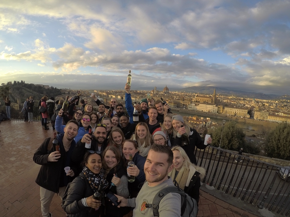 Group celebrating with drinks overlooking a cityscape.