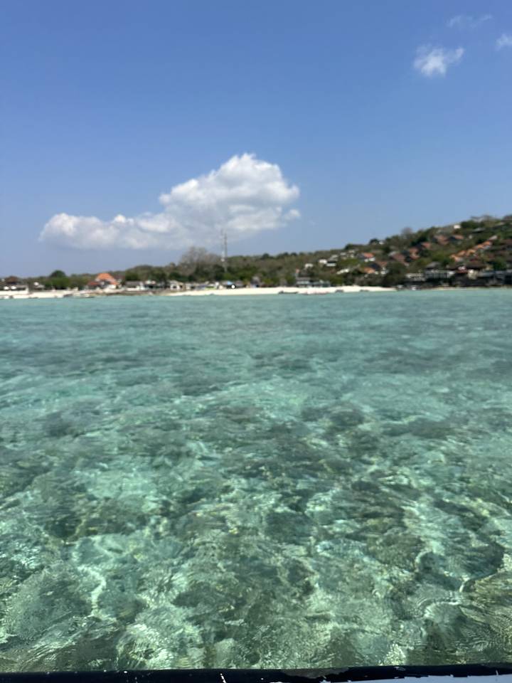 Clear blue water with a horizon and some clouds.