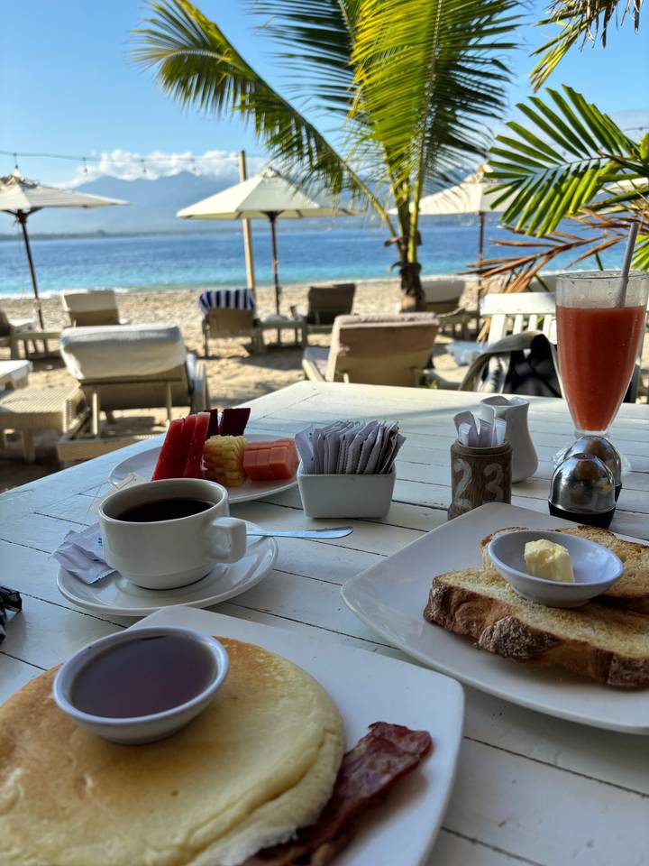 Outdoor breakfast with a view of the sea and palm trees.
