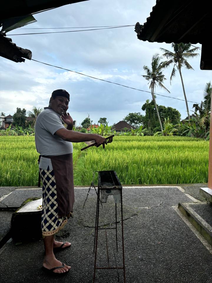 Person grilling food with rice paddies in the background.