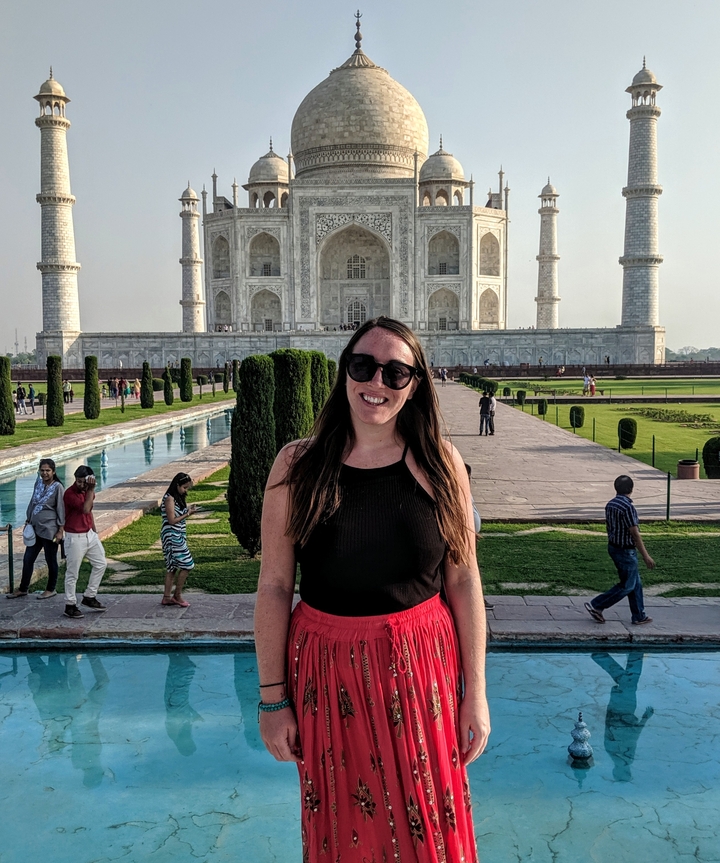 A woman poses in front of the Taj Mahal.