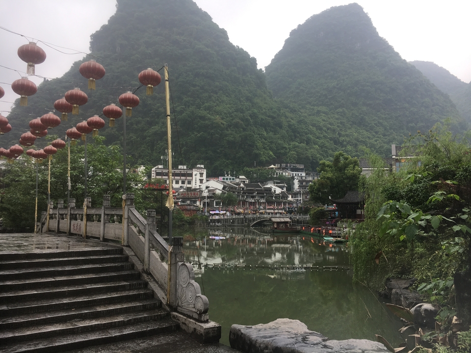Vue pittoresque d'une rivière, de bâtiments traditionnels et de montagnes.