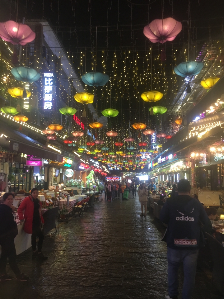 Marché de rue animé avec des lanternes colorées suspendues.