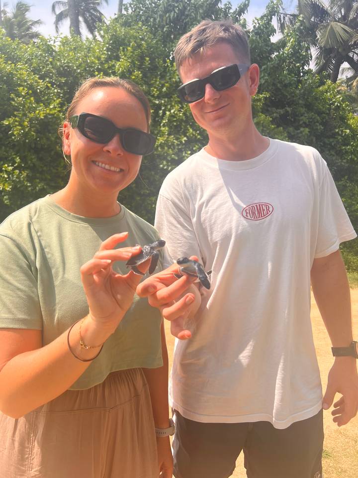 Deux personnes tenant des bébés animaux et souriant à la caméra.