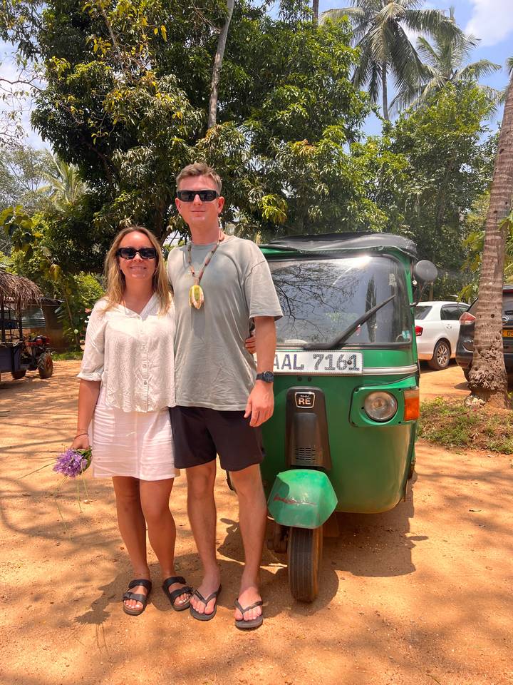 Deux personnes posant avec un tuk-tuk vert sur un chemin de terre.