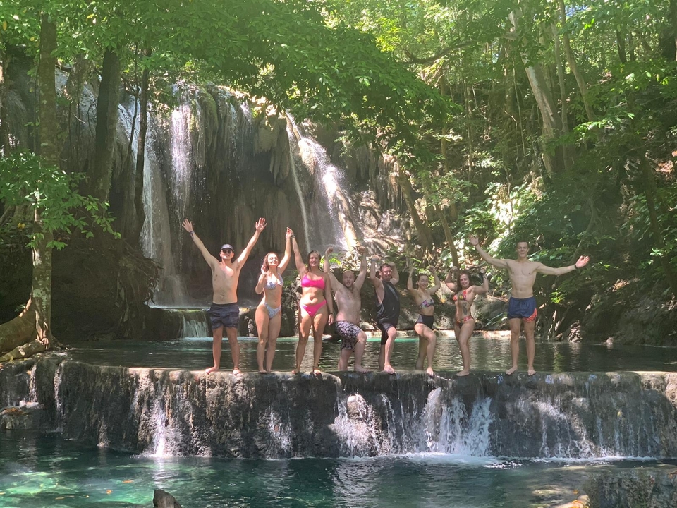 Groupe célébrant près d'une cascade dans une forêt.
