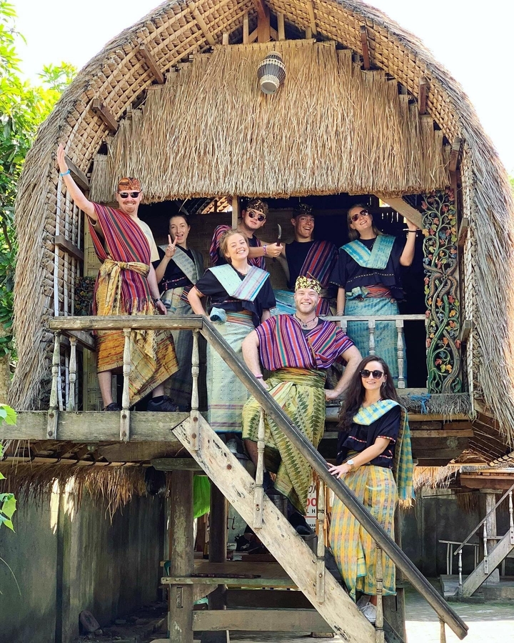 Un groupe de personnes en tenue traditionnelle debout sur un porche.