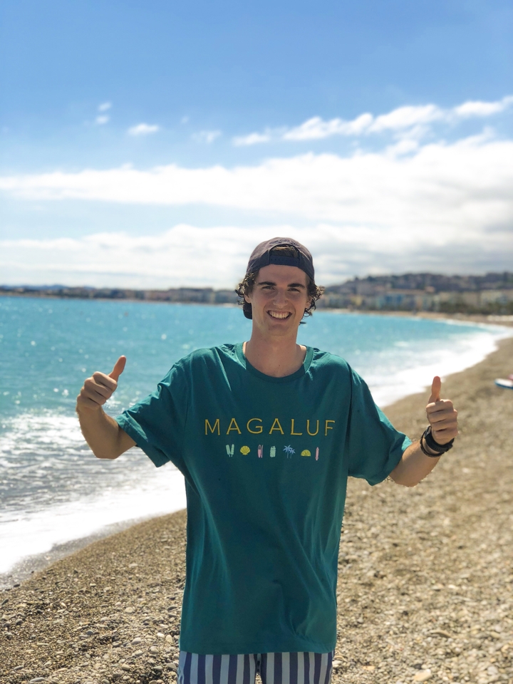 Smiling person by the beach with a view of the ocean.