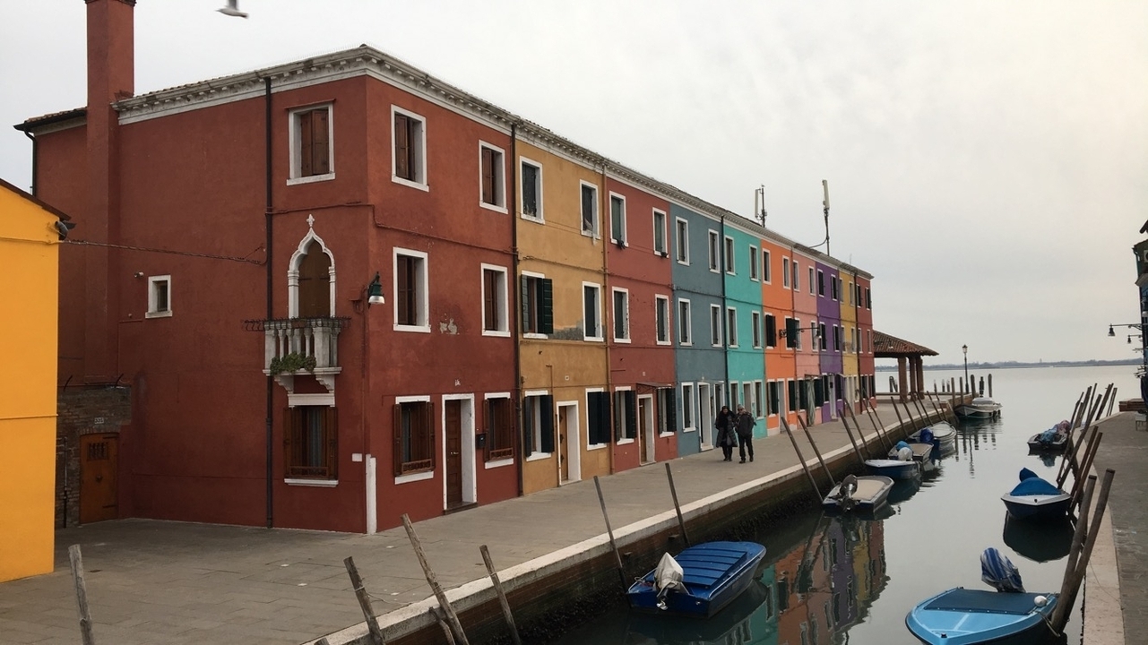 Colorful houses lining a canal with docked boats.
