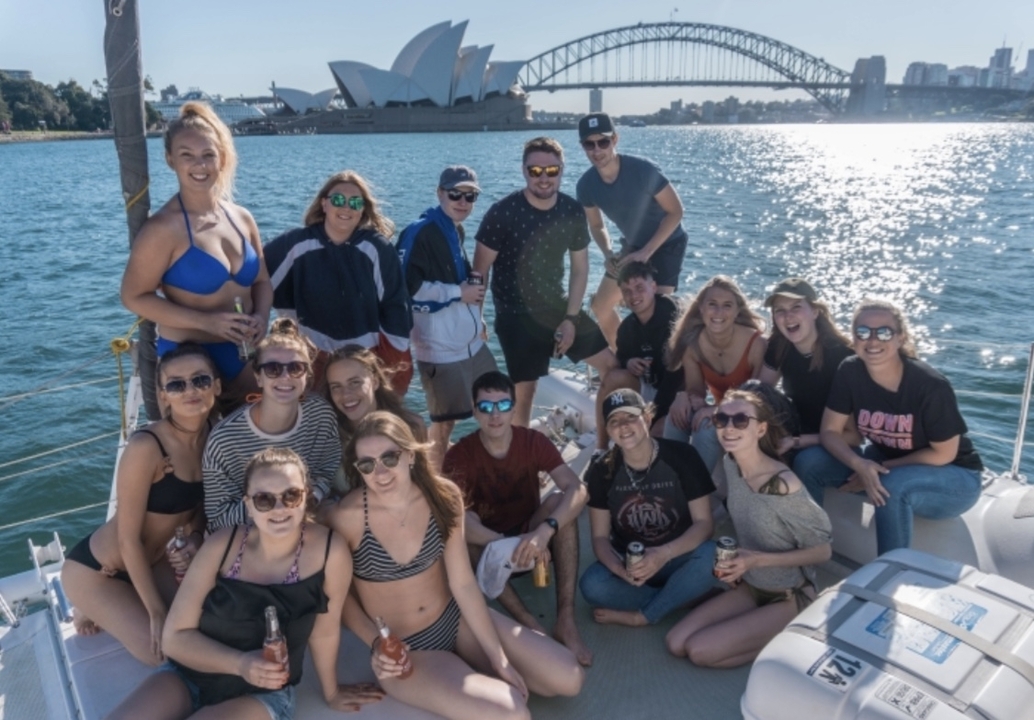 Group of friends posing on a boat with a cityscape in the background.