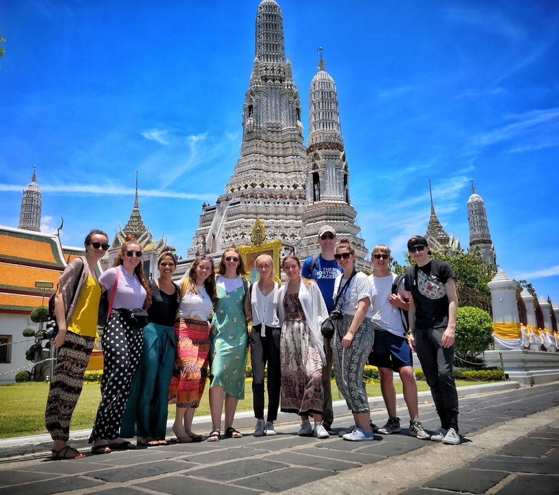Group posing in front of a large temple in bright daylight