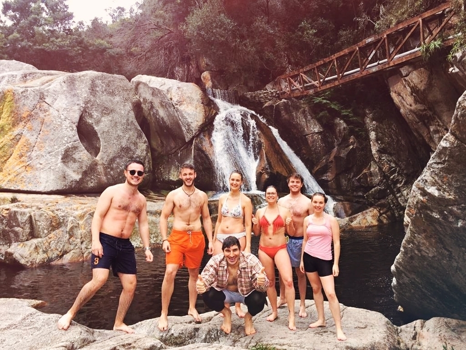 Group of people in swimwear by a waterfall.