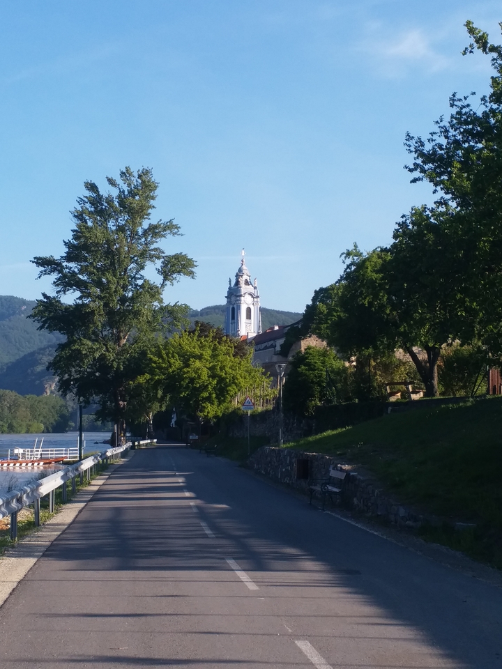 Une tour d'église dans un paysage pittoresque avec des arbres et des collines.