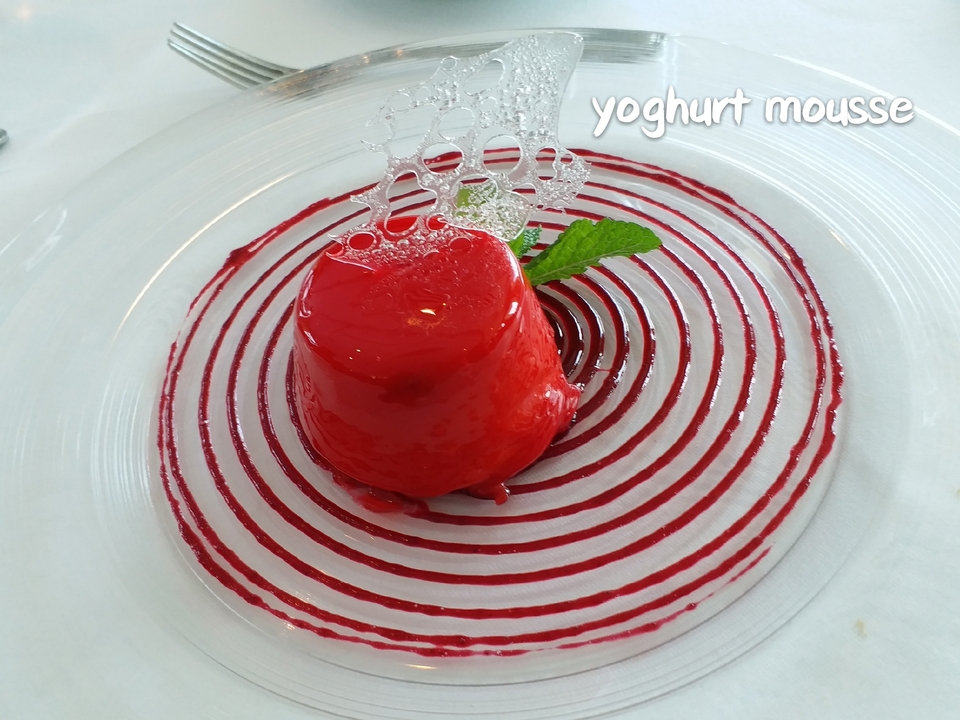Un dessert avec un glaçage rouge et une décoration artistique en chocolat dans une assiette.