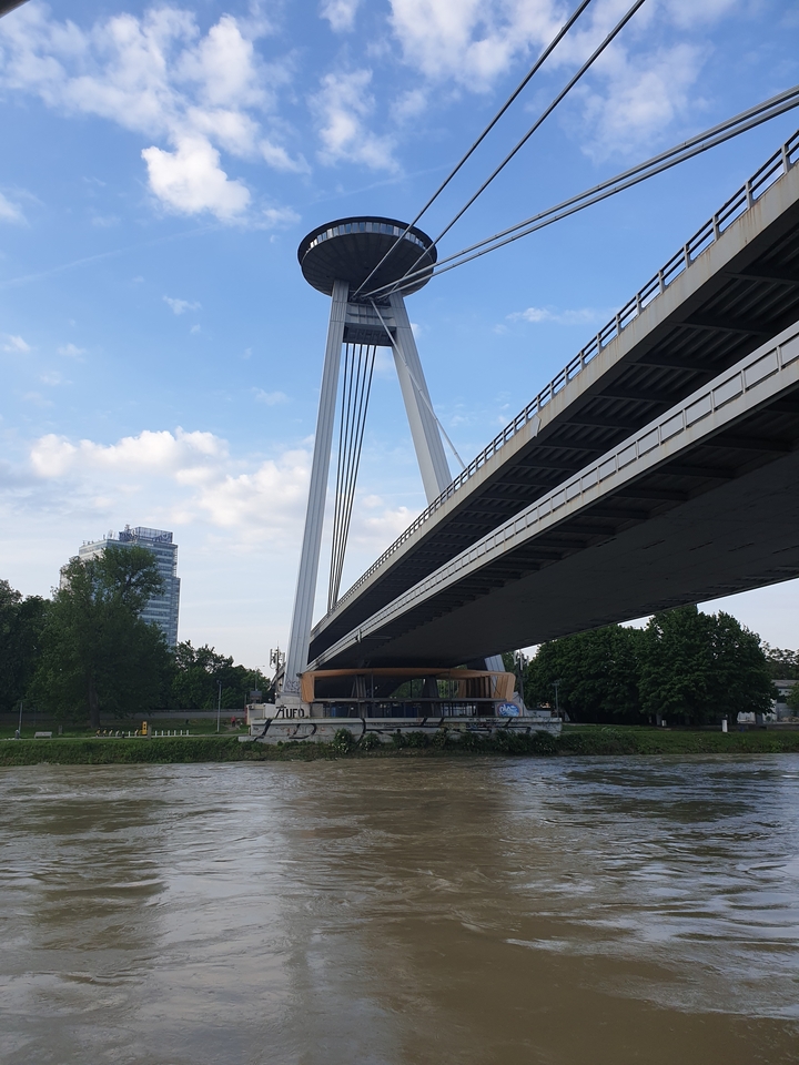 Un grand pont suspendu enjambant une rivière, avec des bâtiments en arrière-plan.