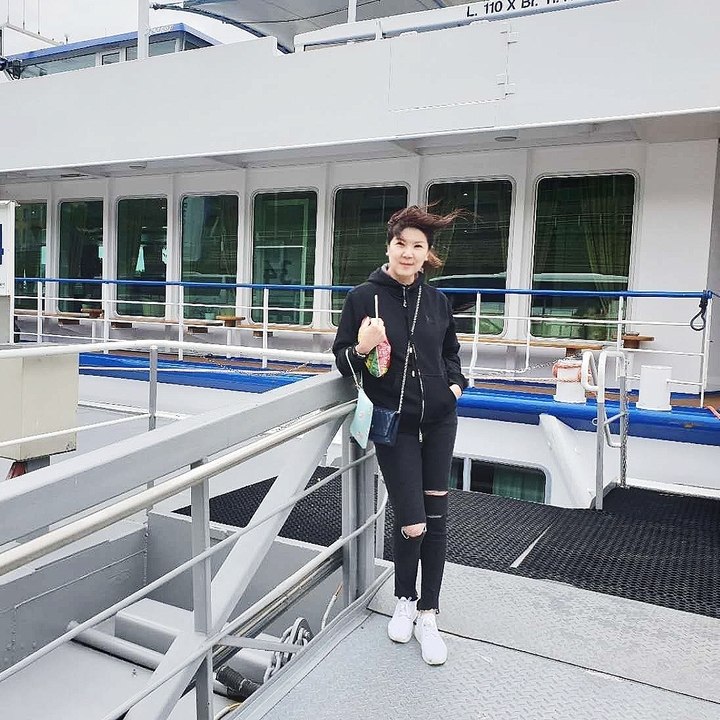 A person standing on the deck of a ship with wind blowing through their hair.