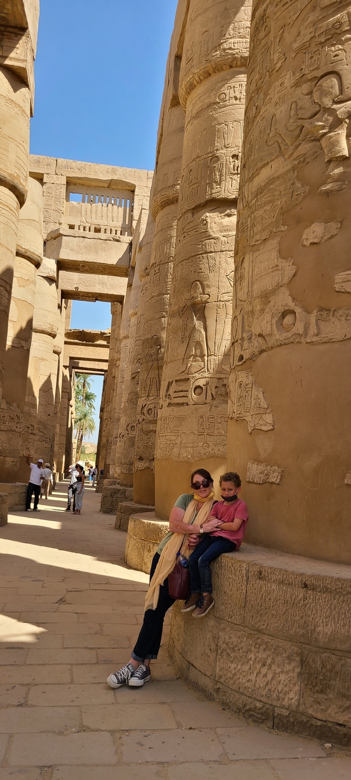 Visitors at an ancient Egyptian temple with hieroglyphs.