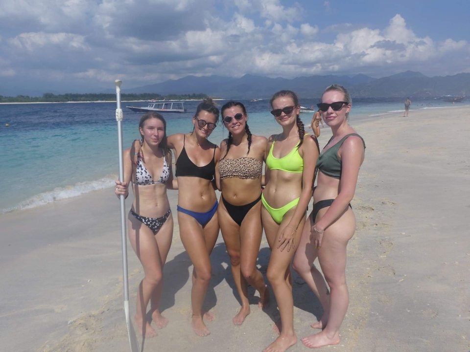 Group of women posing on a sandy beach.