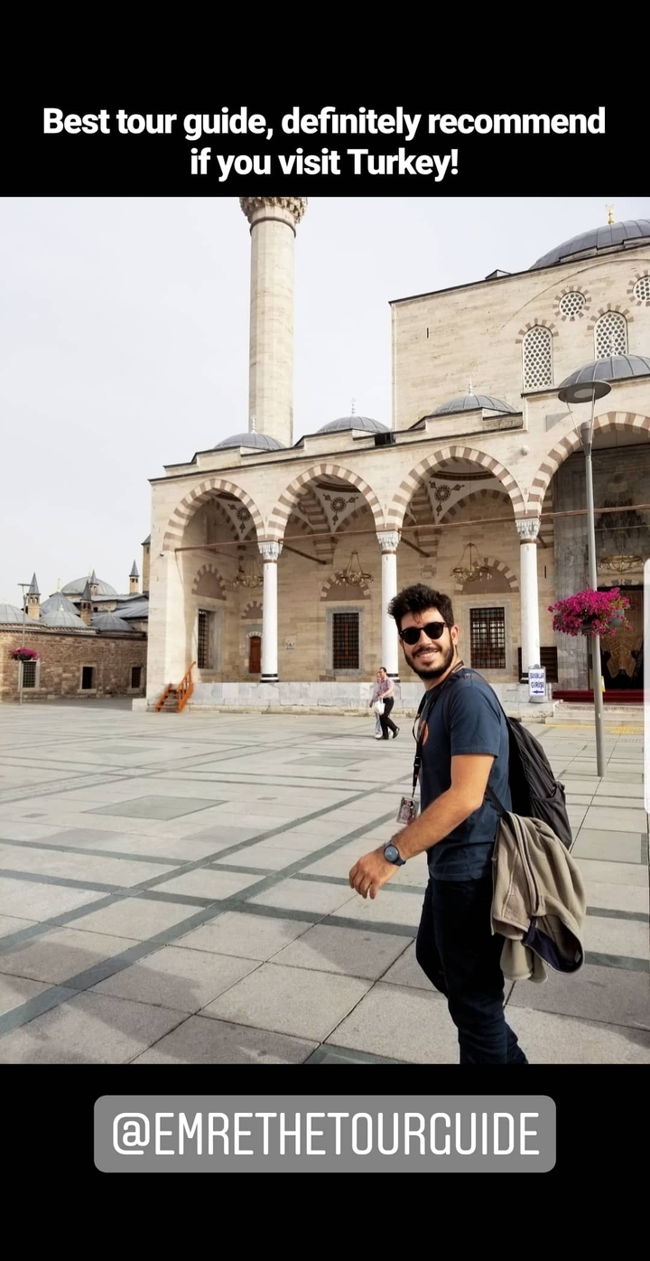 Smiling man posing in front of a historical building with arches.
