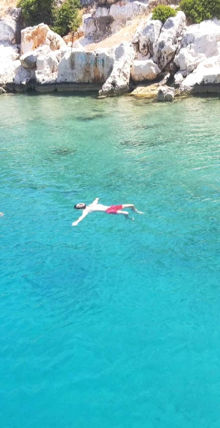 A person floating on clear blue water.