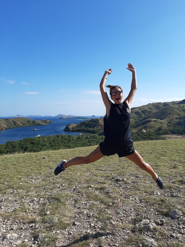 A person jumping in excitement with a scenic view of islands and ocean.
