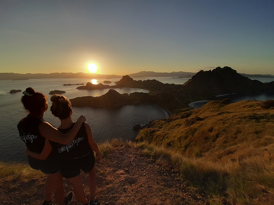 Two people enjoying a sunset view over islands.