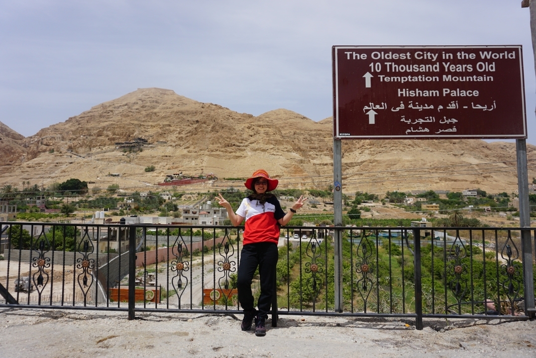 Personne posant devant un panneau pour la Montagne de la Tentation à Jéricho.