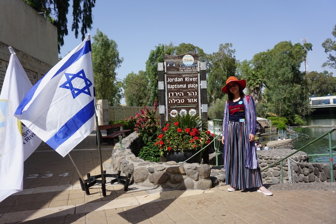 Individu se tenant près du panneau du lieu de baptême du fleuve Jourdain.