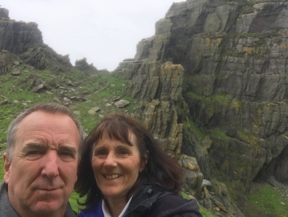 Selfie of a couple with rugged rock formations in the background.