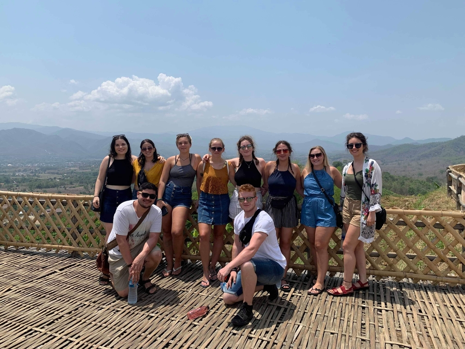 Group of people posing on a bamboo platform with a scenic view.