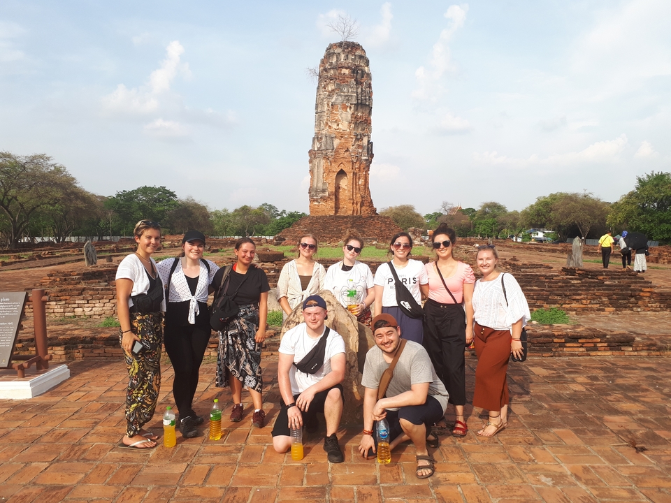 Group of tourists posing in front of a tall ancient temple.