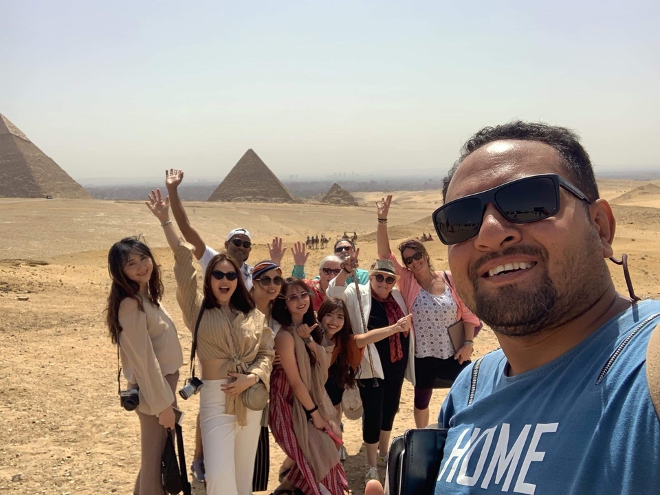 Group of people posing in front of pyramids.
