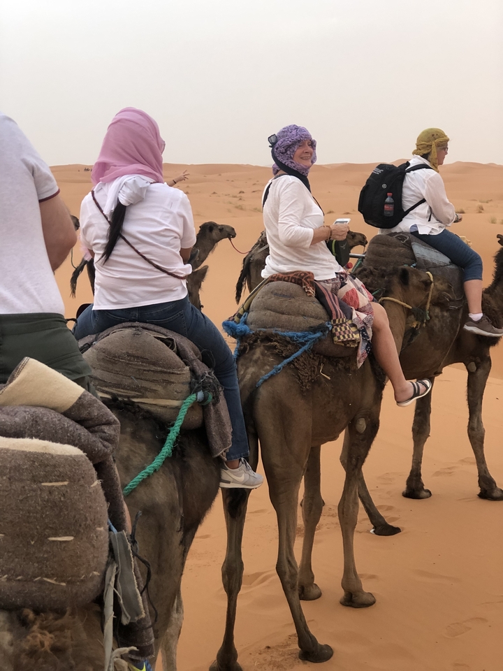 People riding camels in a desert landscape.