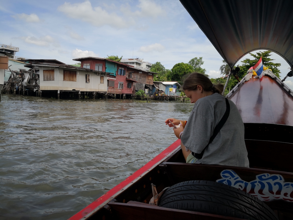 Person on a boat observing traditional riverside houses.