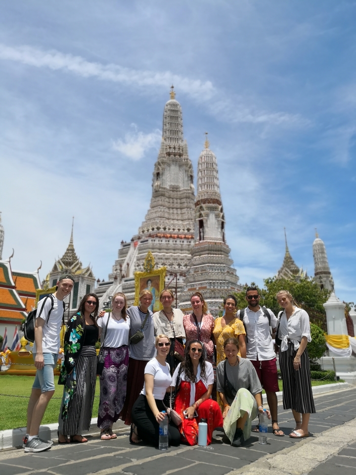 Group of people posing in front of a temple with intricate architecture.