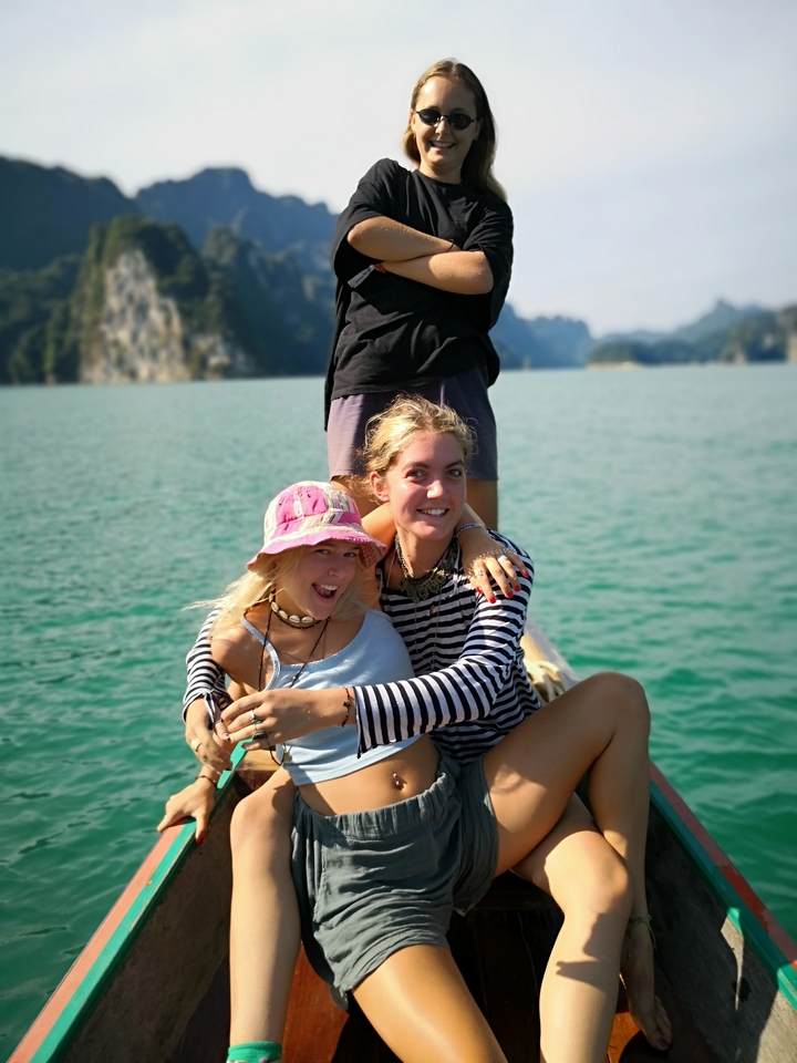 People posing and smiling on a boat with scenic lake and hills.
