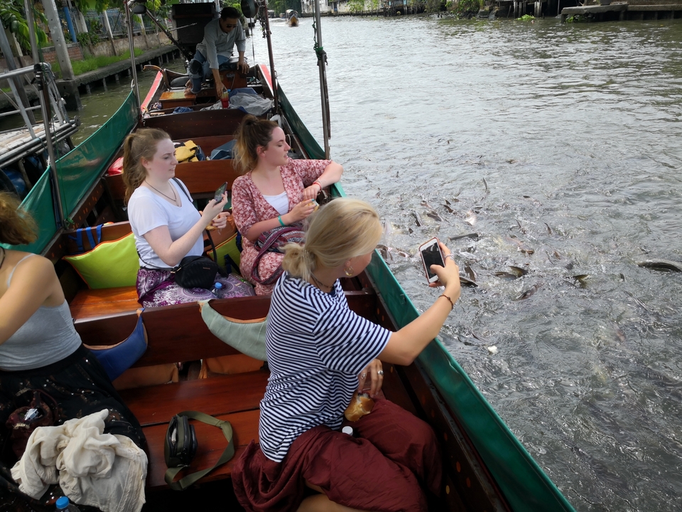 People on a boat interacting with fish in the water.