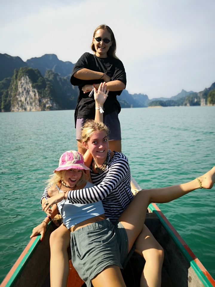 People posing on a boat against the backdrop of a lake and hills.