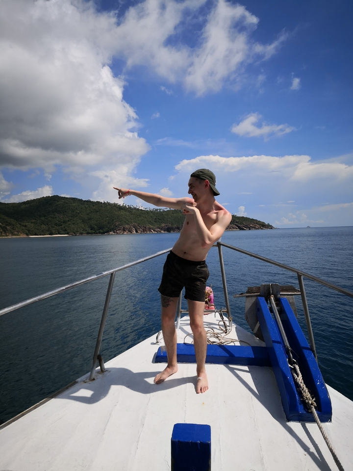 Person pointing from the bow of a boat.