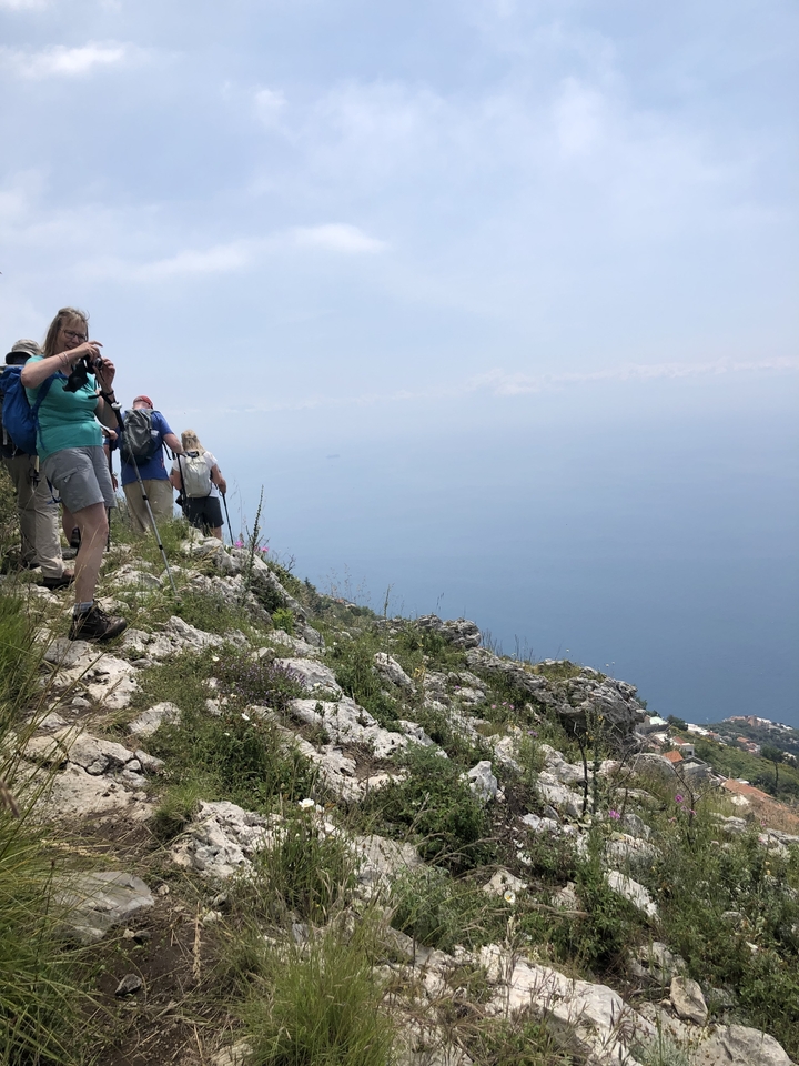 Des gens qui font de la randonnée sur un sentier rocheux avec une vue sur la mer.