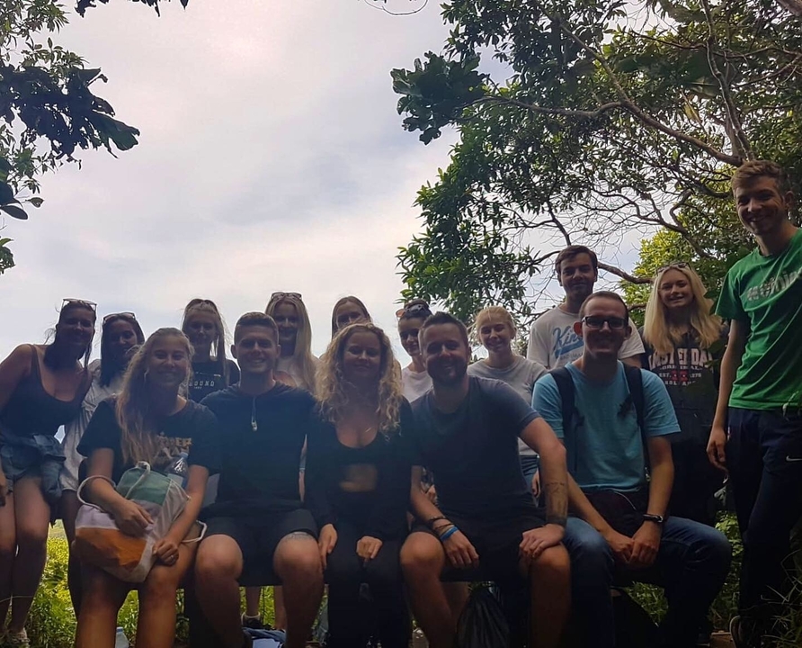 Group of people posing outdoors with trees.