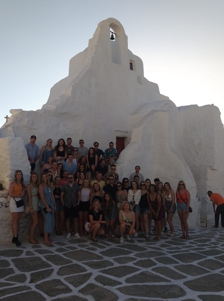 Large group of people posing in front of a white building.