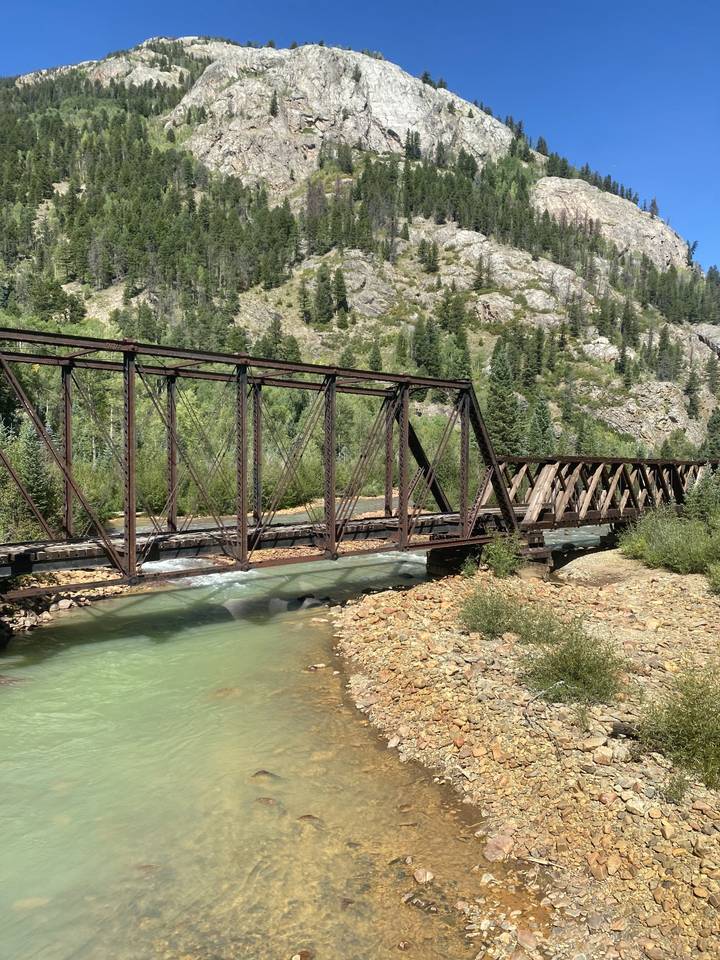 Pont ferroviaire au-dessus d'une rivière dans une zone boisée.