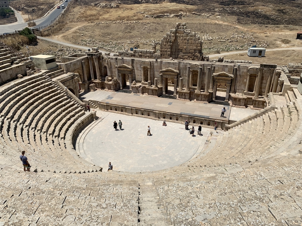 Ancient Roman theater with people walking around.
