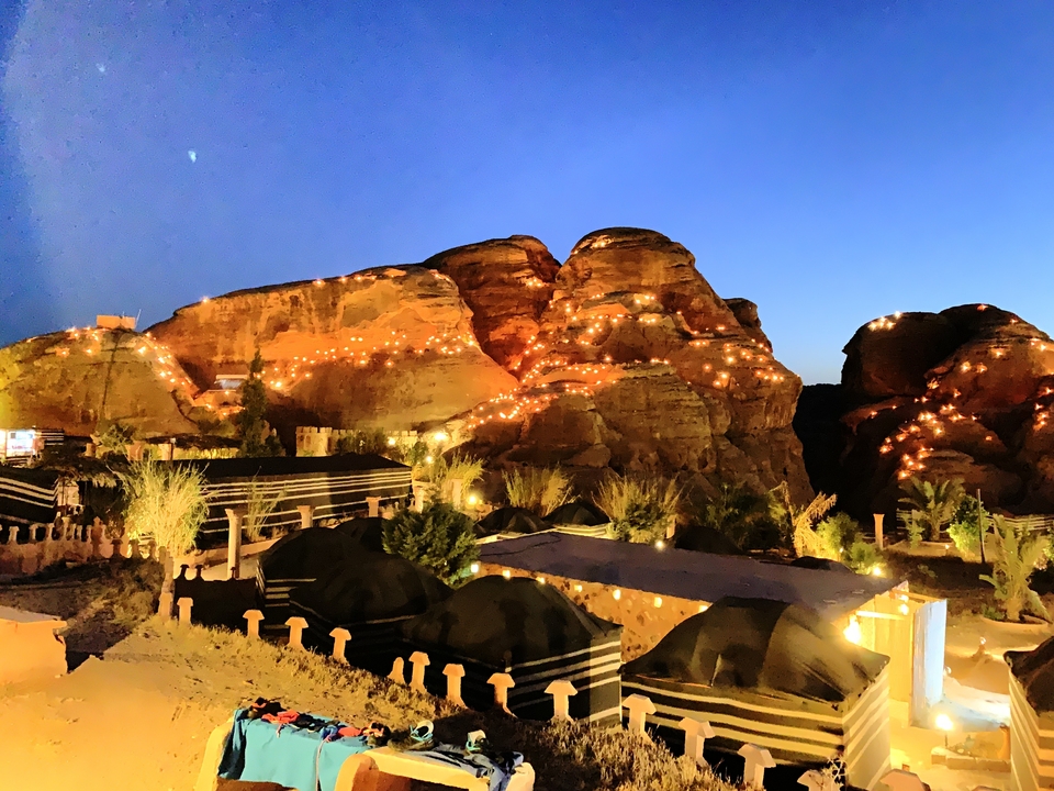 Petra at night with illuminated hills and tents.