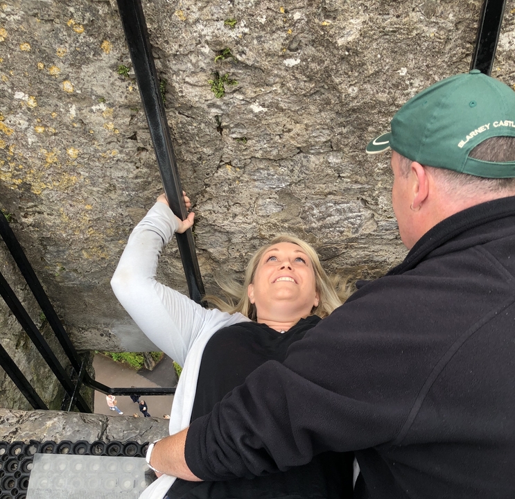 Personne embrassant la pierre de Blarney avec assistance.