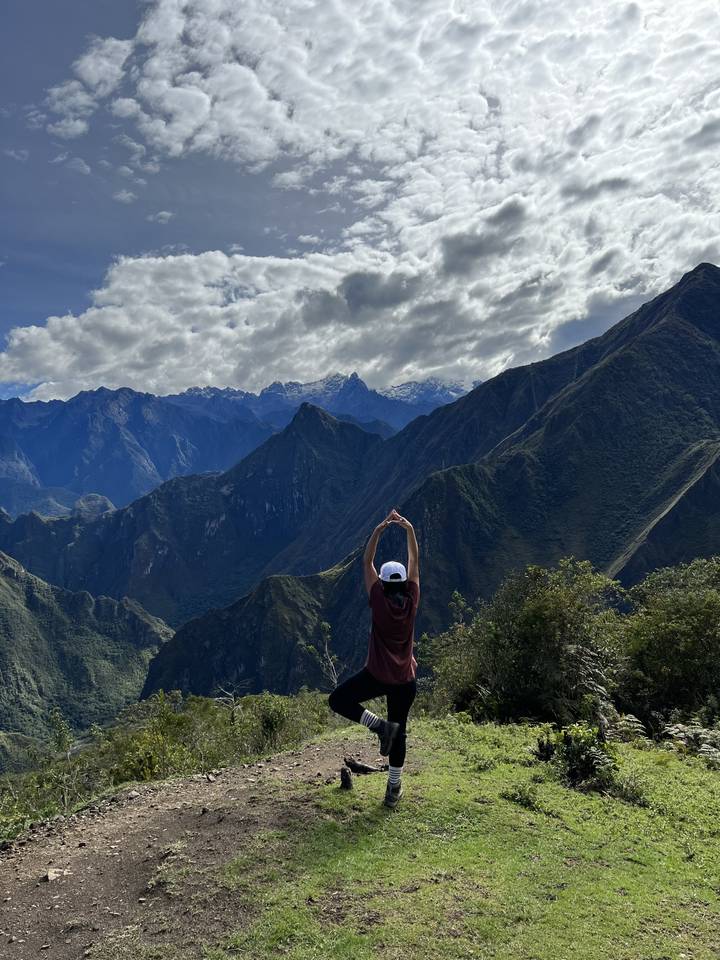 Individual with arms raised facing mountain range.