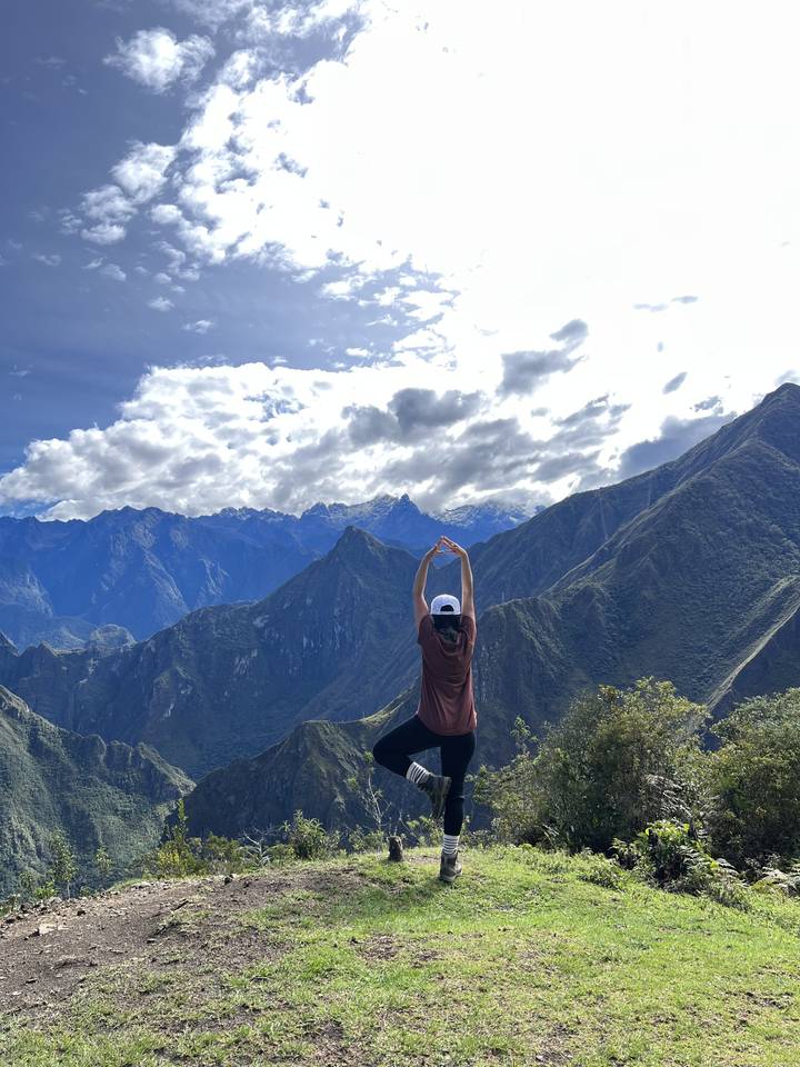 Person stretching arms with mountains in the distance.