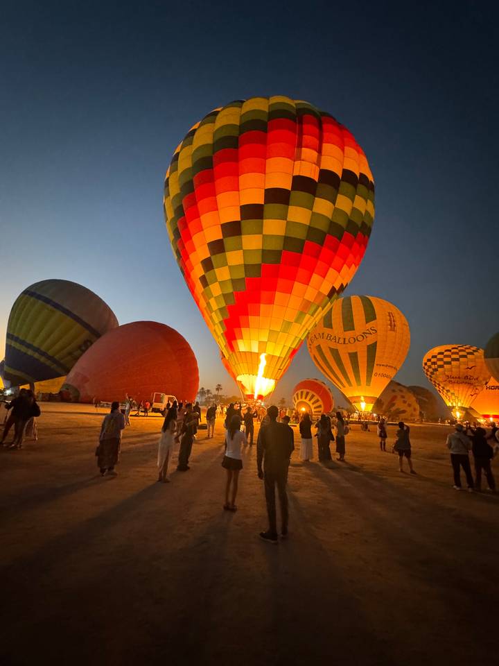 Hot air balloons being inflated with people around
