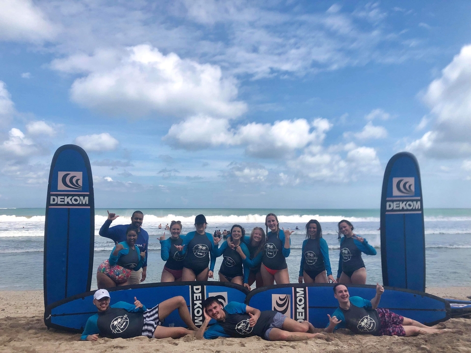 Group of people standing on a beach next to surfing boards.